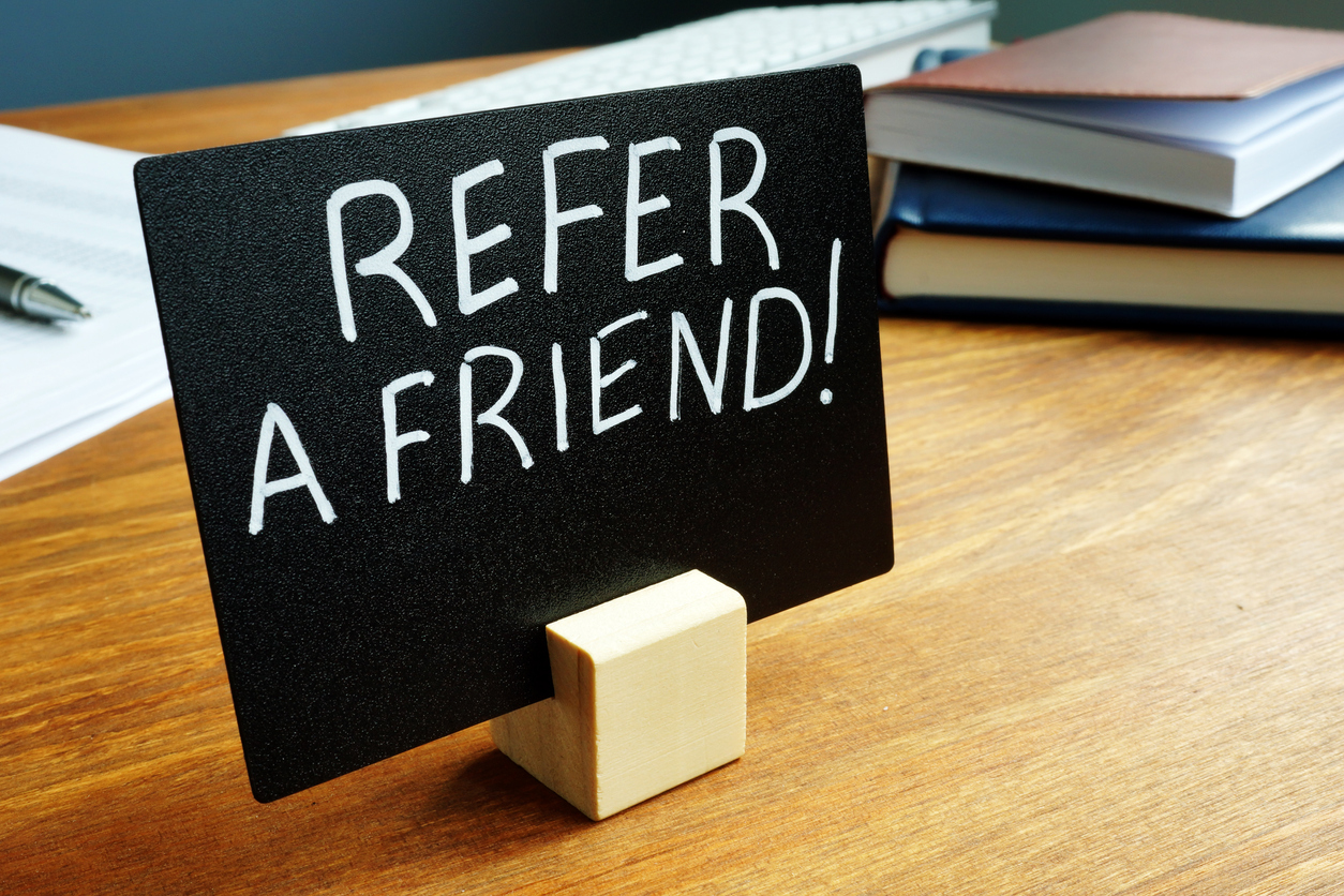 Refer a friend concept plate on the desk. Refer a friend concept plate on the desk.